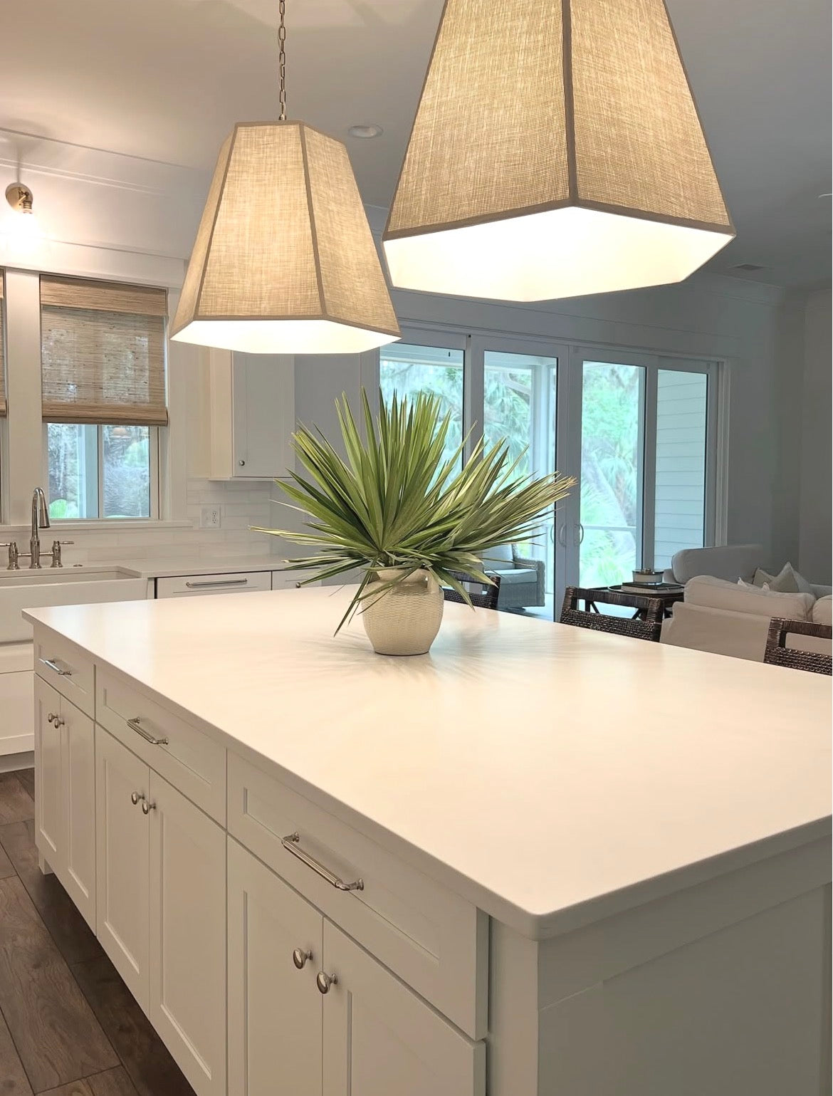 Bright white kitchen with linen pendants and a fan palm arrangement